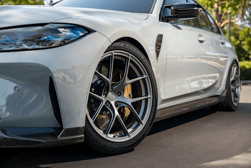 Vista lateral de llanta Yokohama ADVAN Sport V107 en auto deportivo blanco, con frenos de disco perf