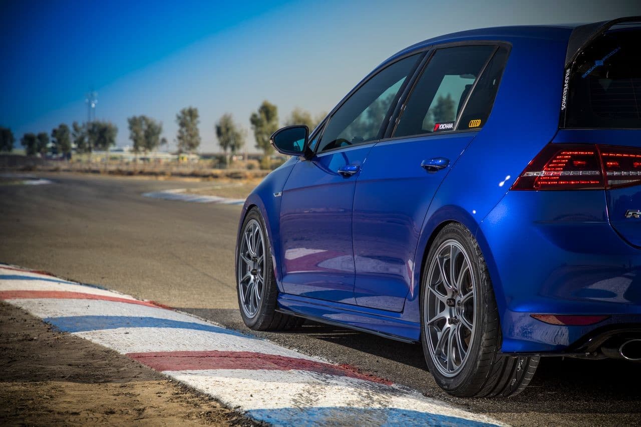 Volkswagen Golf R azul en pista de carreras, equipado con llantas Yokohama ADVAN Fleva V701 y rines 