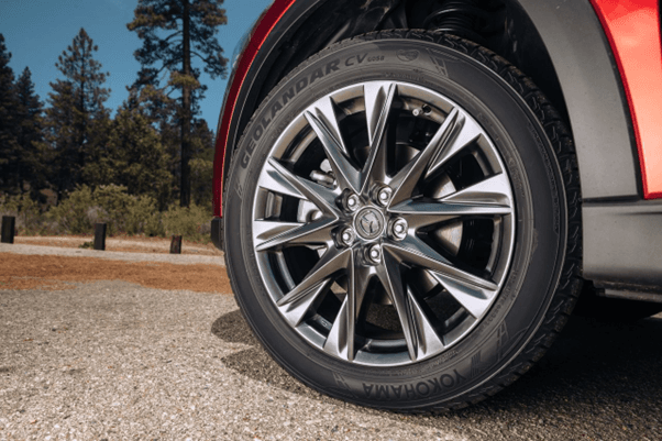 Vista cercana de la rueda delantera de un SUV rojo con llanta Yokohama Geolandar CV G058 y rin de mú