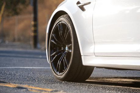 Primer plano de la rueda delantera de un sedán blanco con llanta Yokohama ADVAN Apex, mostrando el r