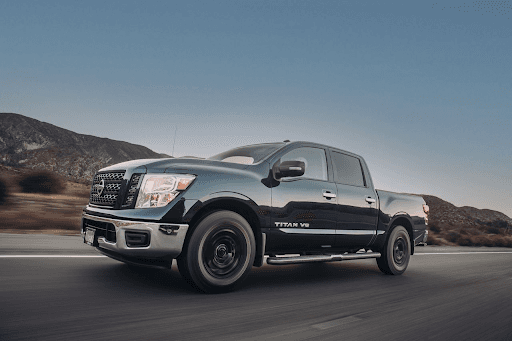 Camioneta Nissan Titan V8 negra en movimiento sobre carretera, con montañas y cielo despejado al fon