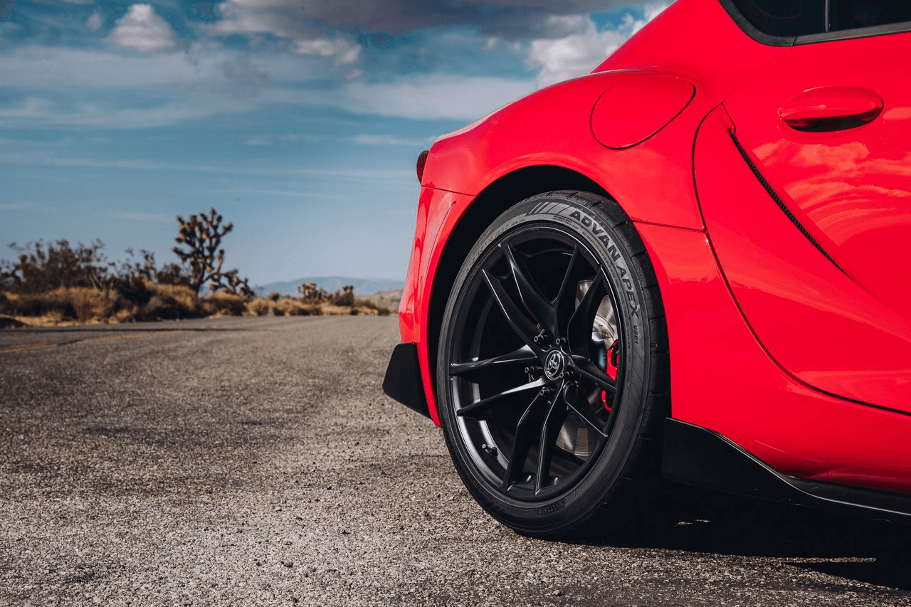 Toyota Supra rojo con llantas Yokohama ADVAN Apex V601 sobre carretera abierta, diseñado para máxima