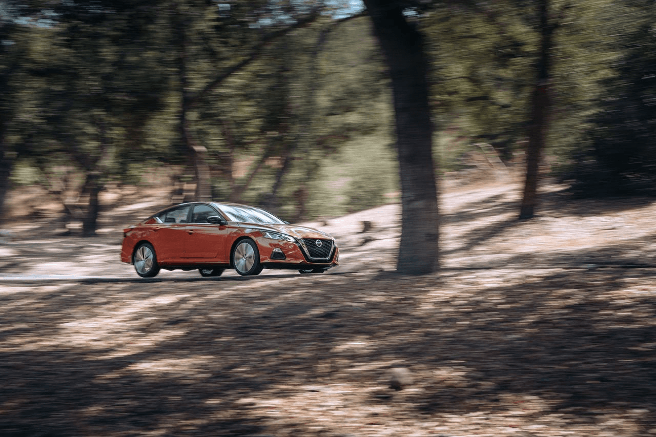 Auto familiar Nissan circulando entre árboles, equipado con neumáticos Yokohama.
