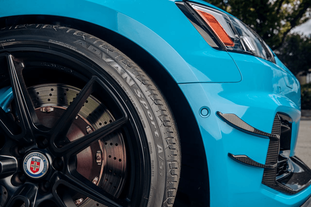 Detalle de llanta Yokohama ADVAN Sport A/S+ en vehículo deportivo azul, mostrando tecnología y diseñ