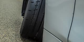 Primer plano de una llanta de automóvil junto a la carrocería, con el neumático girado hacia afuera
