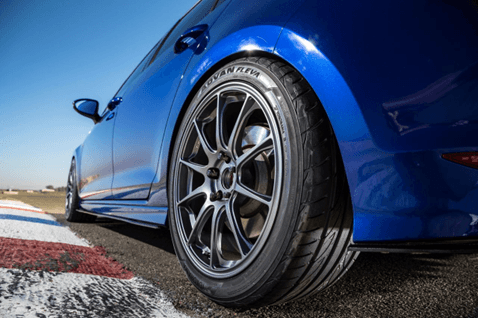 Primer plano de una llanta Yokohama Advan Fleva V701 montada en un vehículo deportivo azul sobre una