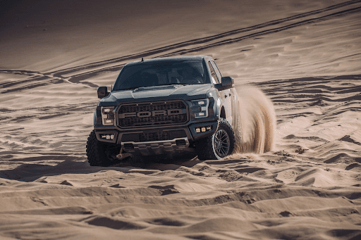 Pickup Ford Raptor equipada con llantas Yokohama Geolandar M/T G003 cruzando dunas de arena con gran