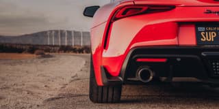 Parte trasera de un automóvil deportivo rojo con una llanta lisa visible, en una carrete
